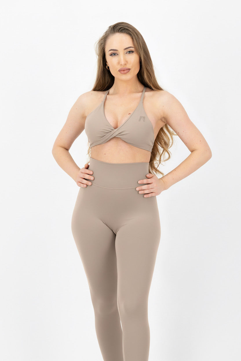 Woman wearing a beige bodysuit on a white background