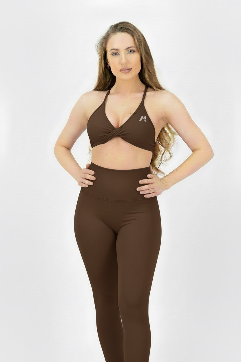 Woman wearing a brown sports bra and leggings set on a white background